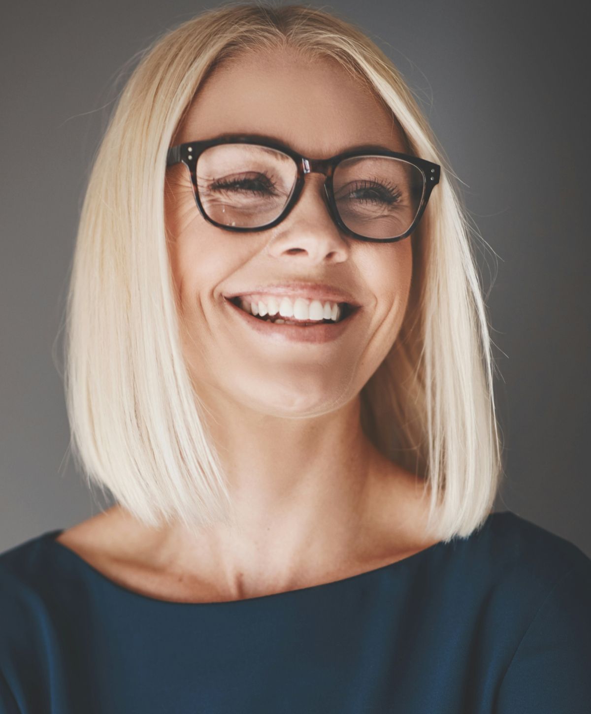 Smiling woman with glasses and blonde hair.