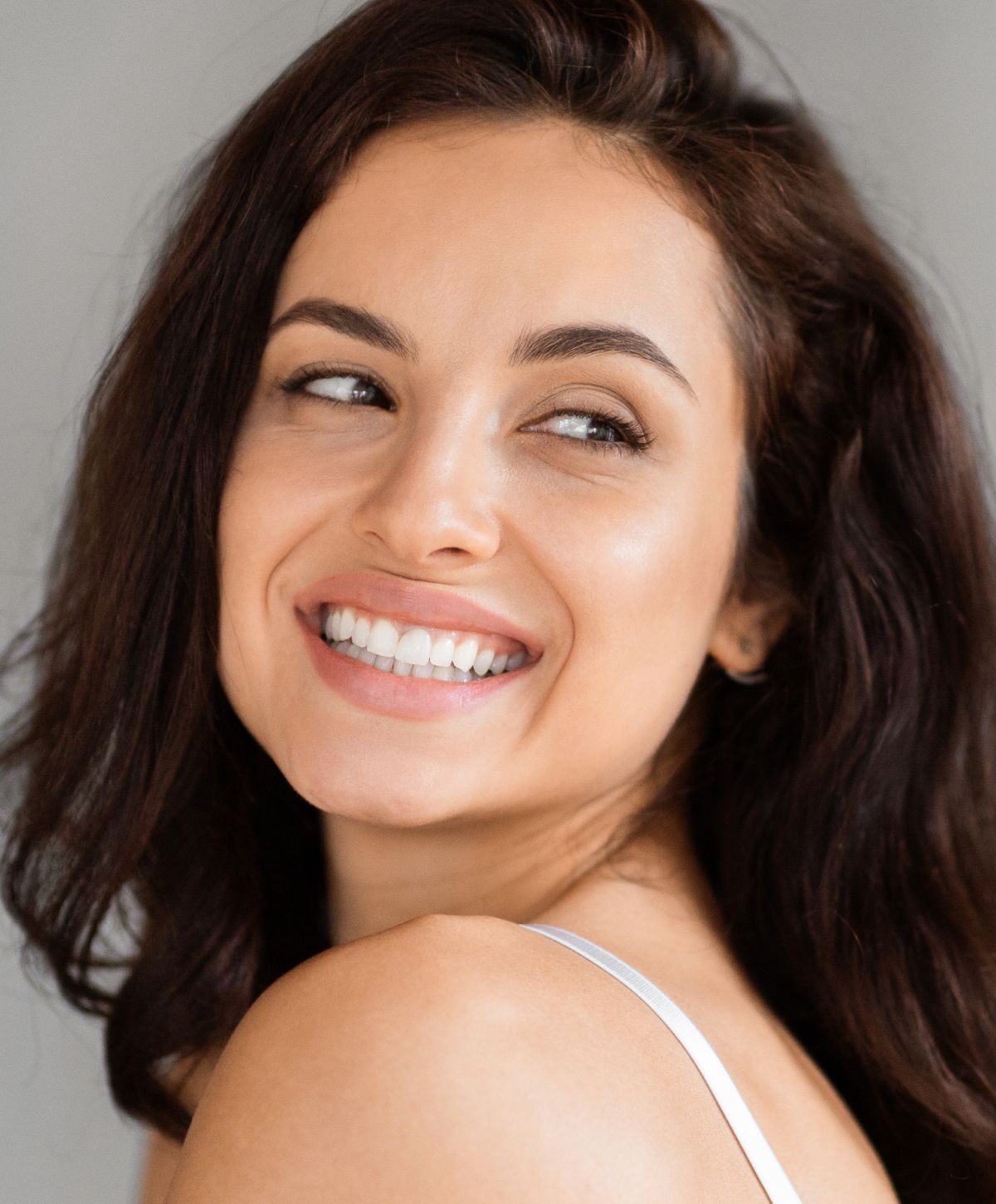Smiling woman with dark hair and glowing skin.