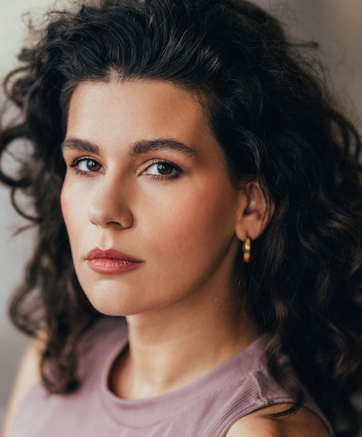 Woman with curly hair and neutral makeup.