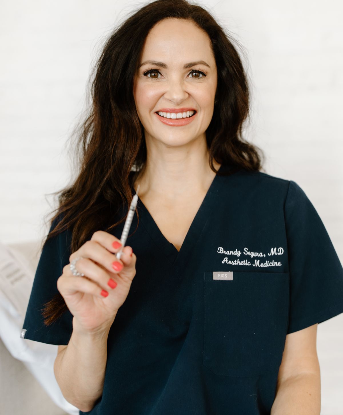 Aesthetic doctor smiling with a syringe in hand.