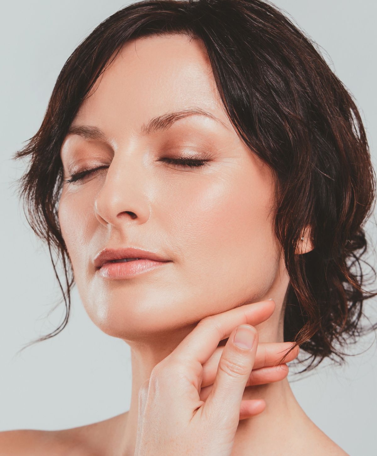 Woman touching her neck with closed eyes.