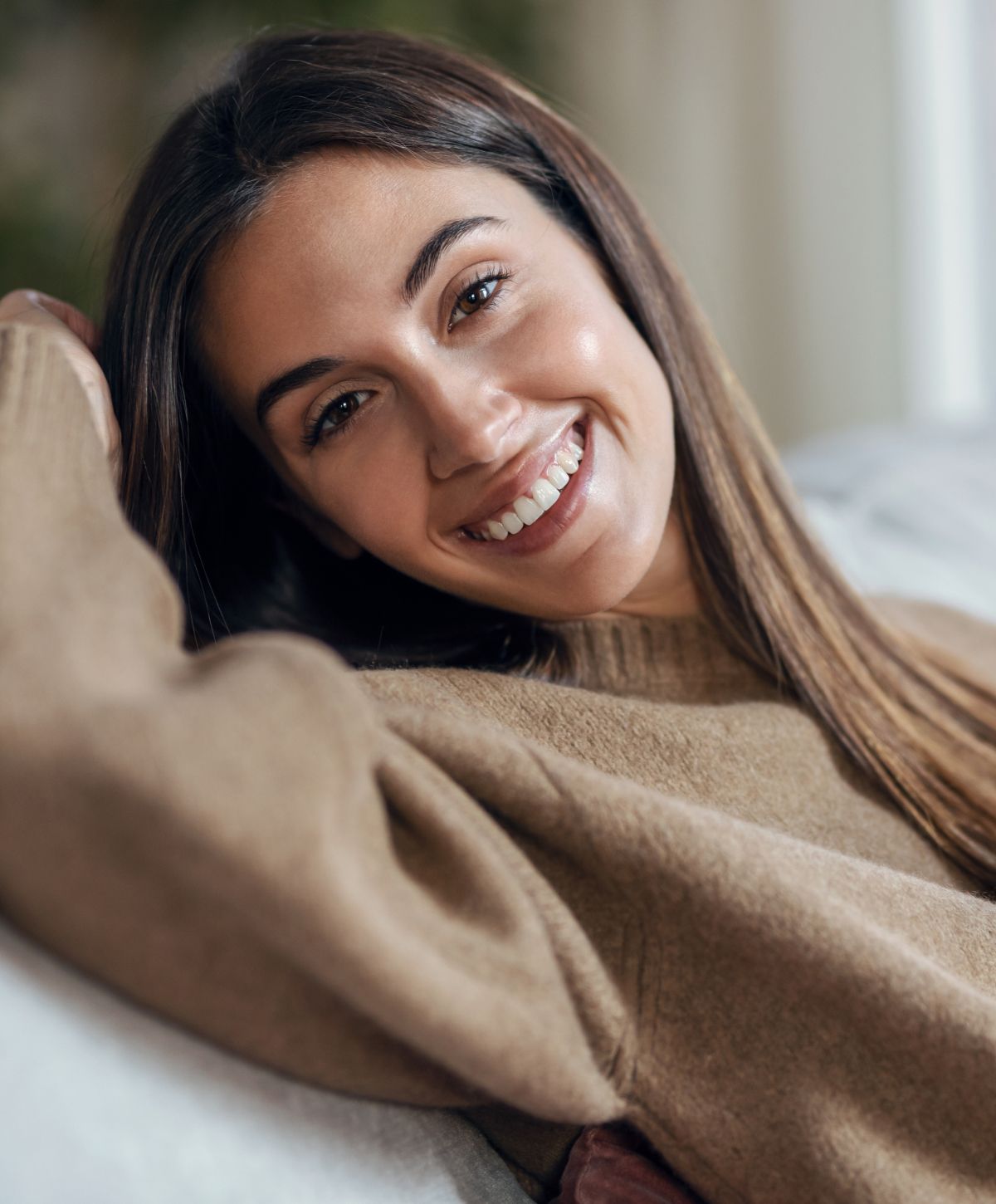Smiling young woman in cozy sweater at home.